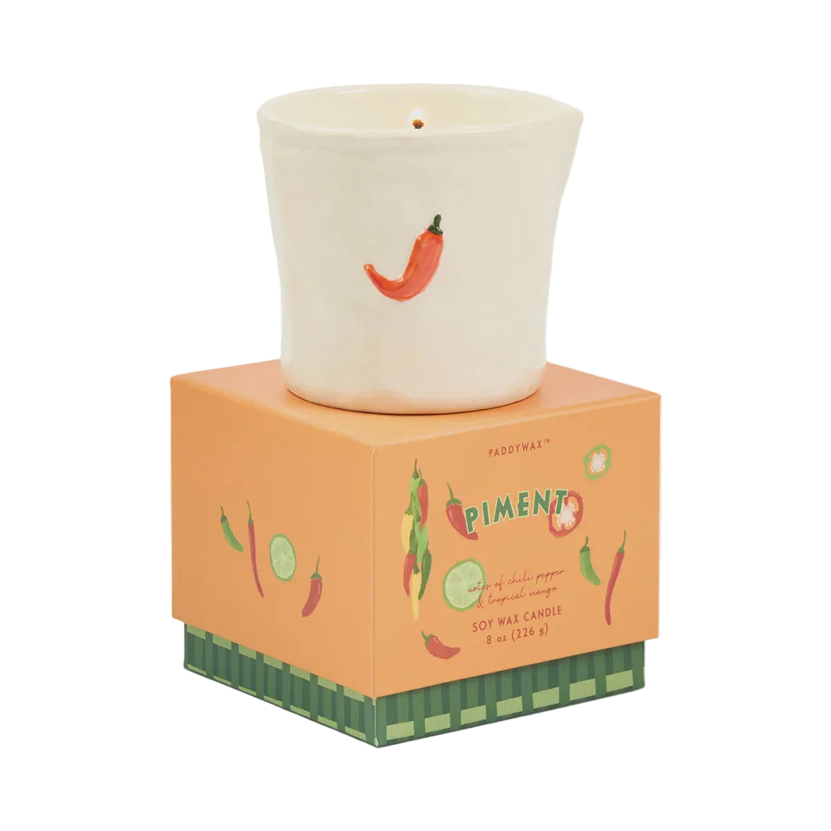 A Paddywax Piment soy wax candle in an off-white ceramic pot with a red chili pepper illustration, displayed on top of its orange and green packaging box against a light gray background.