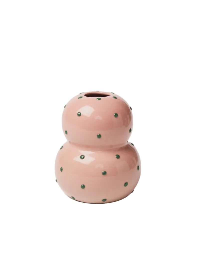 Pink ceramic vase with green polka dots on a white background